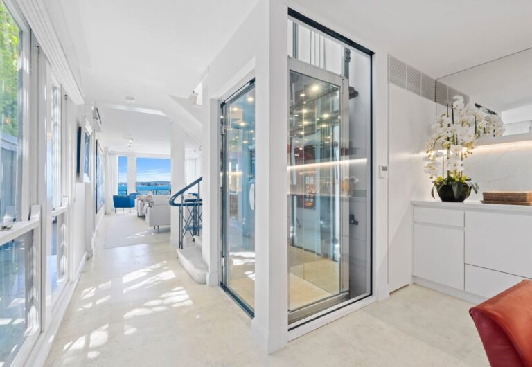 Glass-walled lift integrated into luxury home interior corridor
