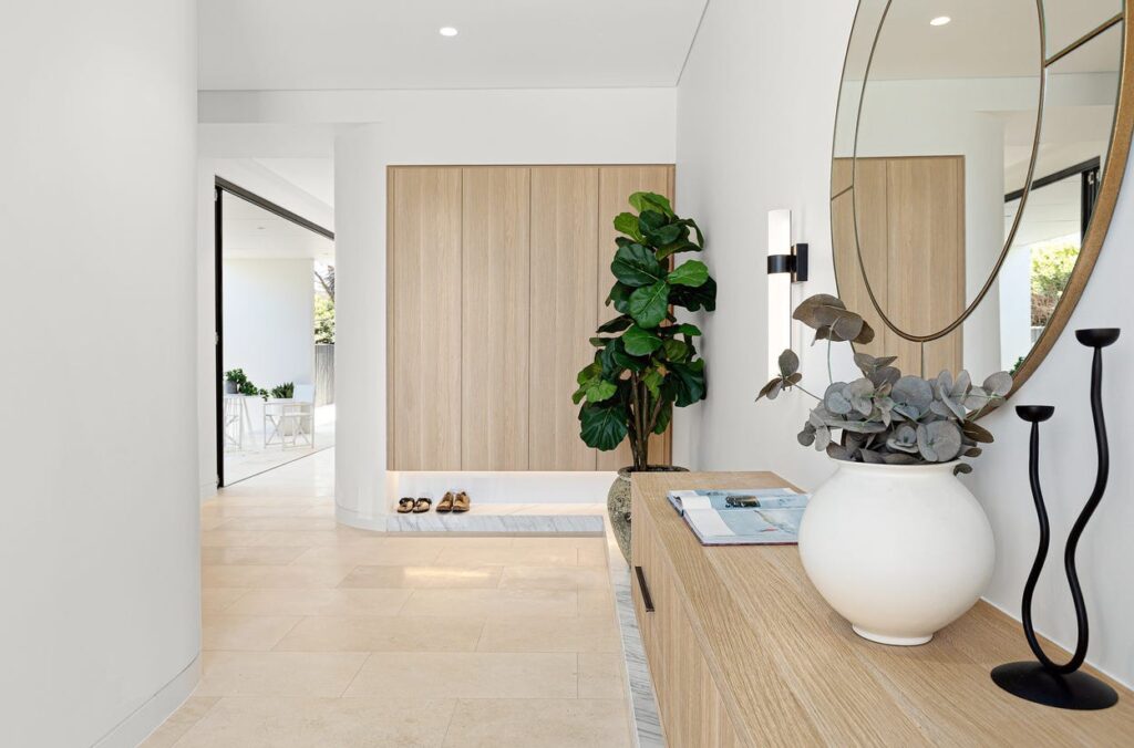 Entry hall of the Northern Sydney home with a timber panel, round mirror and sideboard, leading toward the A Series lift