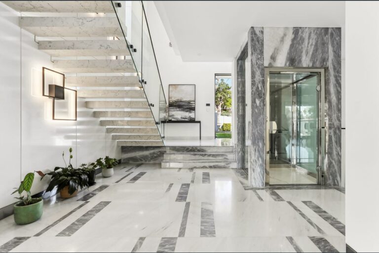 Glass home lift in a marble surround beside a floating marble staircase in Strathfield