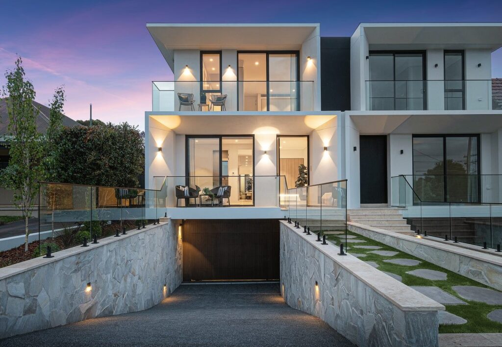 Modern three-level prestige home in north-west Sydney at dusk, with glass balustrades and a basement garage