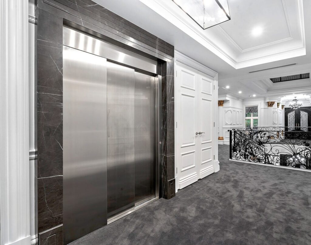 Stainless sliding lift doors in a dark stone surround beside white panelling in Balwyn