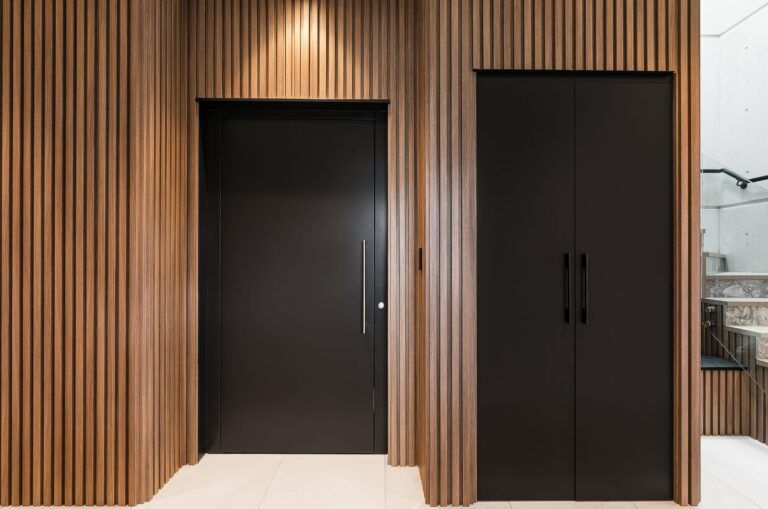 Black lift door set into a timber-slat feature wall in Caringbah South