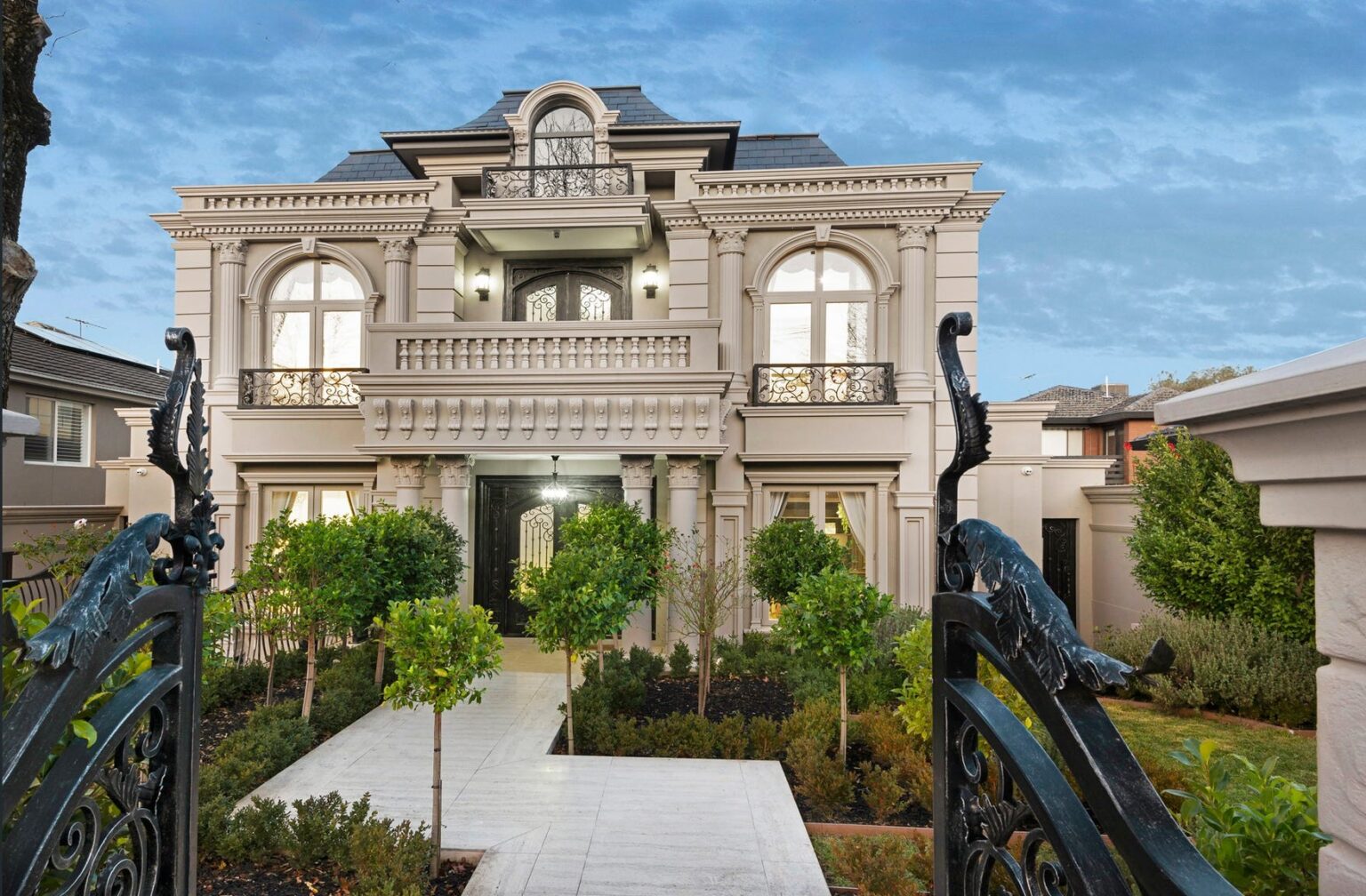 French Provincial home in Balwyn with a Spanish slate roof, arched windows and wrought-iron gates