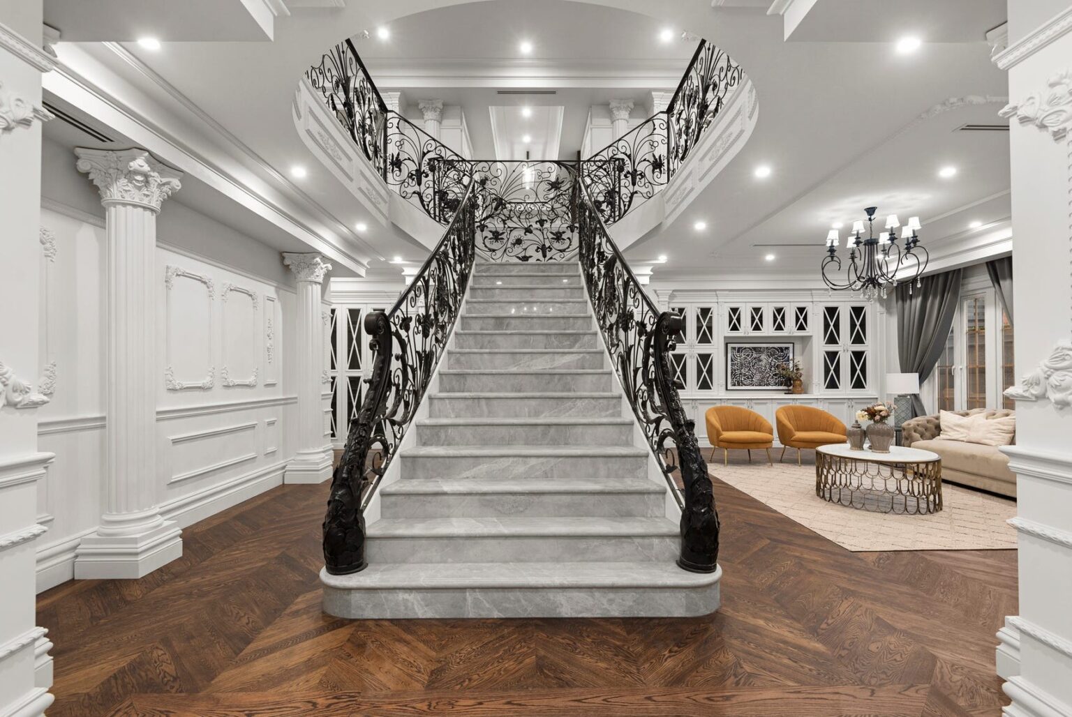 Sweeping marble staircase with ornate wrought-iron balustrades in the entry of a French Provincial home in Balwyn