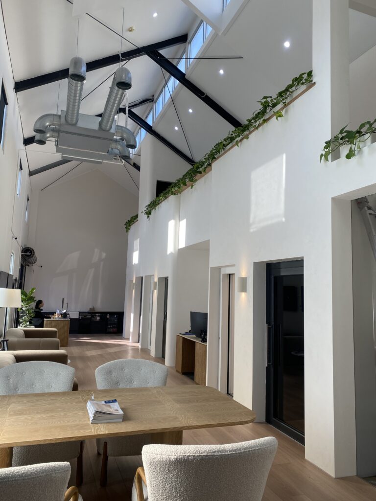 Freestanding dark glass Lift Shop home lift in a barn-style living space with vaulted ceiling