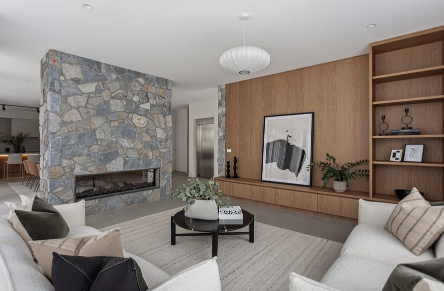 Luxury living room with feature stone fireplace and integrated home elevator in Kew residence
