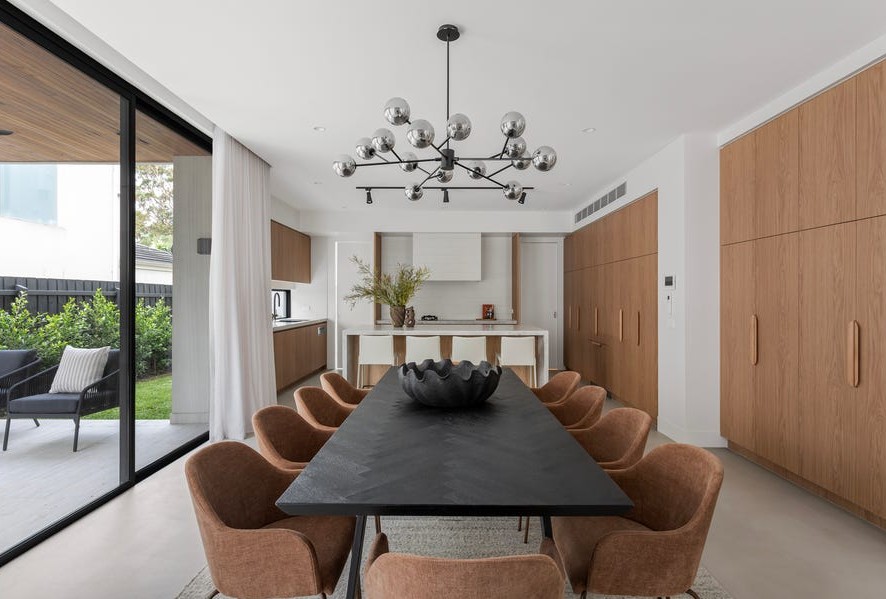 Open-plan dining and kitchen area within luxury Kew home featuring contemporary timber cabinetry