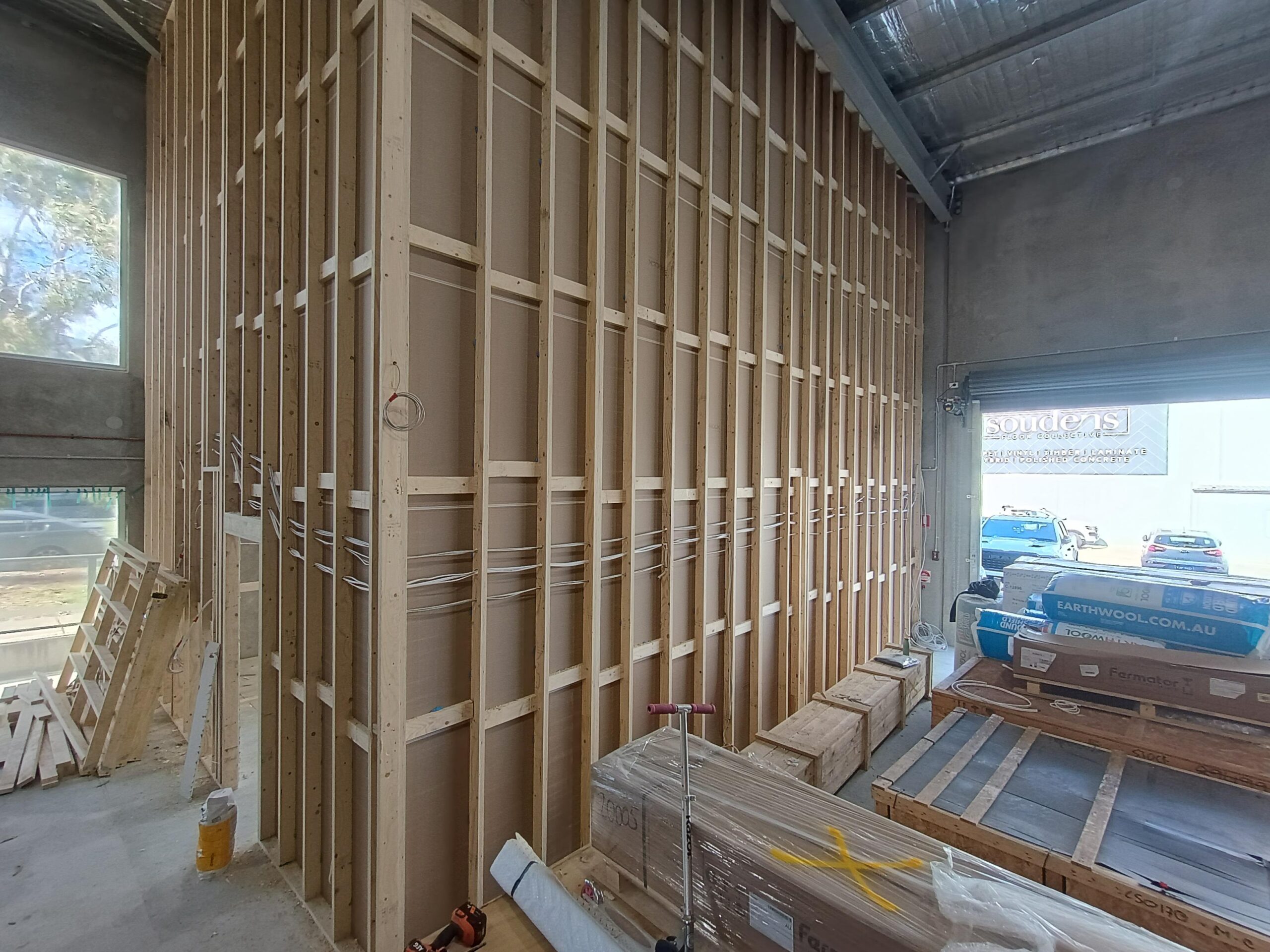 Timber wall framing for the display lift shafts at the Lift Shop Canberra showroom, with lift doors and materials crated on site