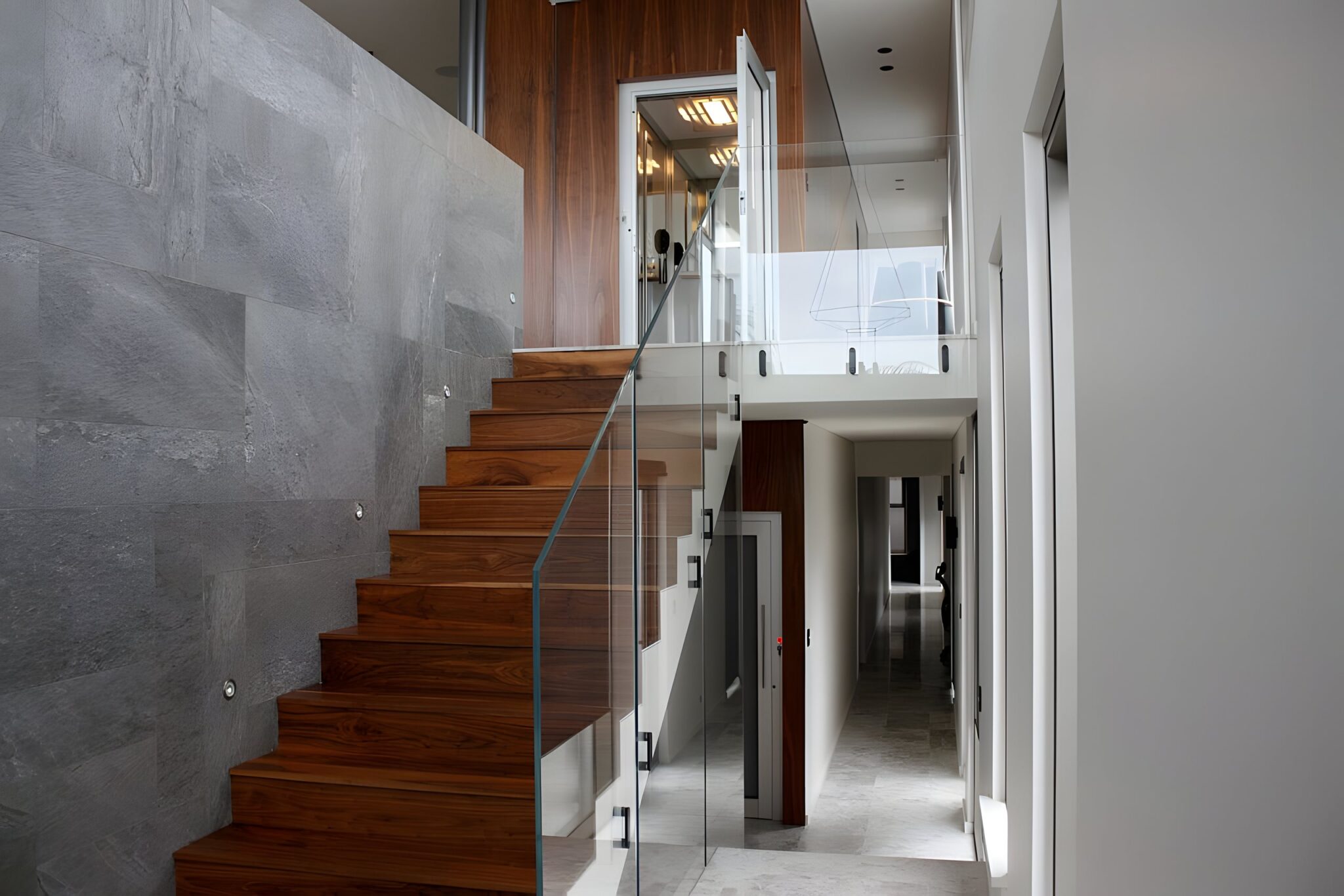 Timber stairs with a glass balustrade leading up to the timber-clad ElfoLift shaft in a City Beach home, Perth
