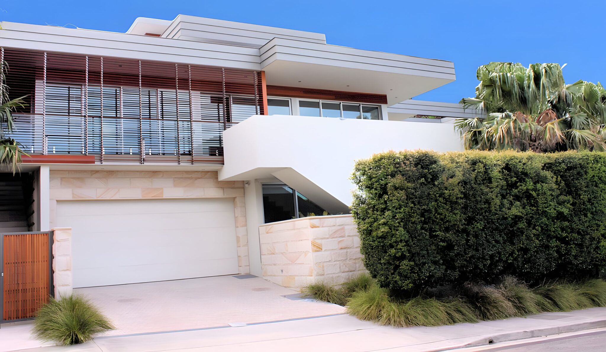 Modern Bellevue Hill house with a timber slatted upper level, sandstone base and a clipped hedge beside the street