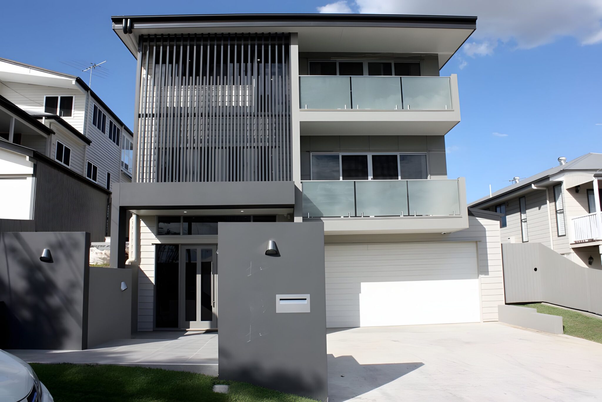 Three storey modern home in Brisbane with slatted screens and frosted glass balconies, the builder's own home with a glass shaft lift at the entrance