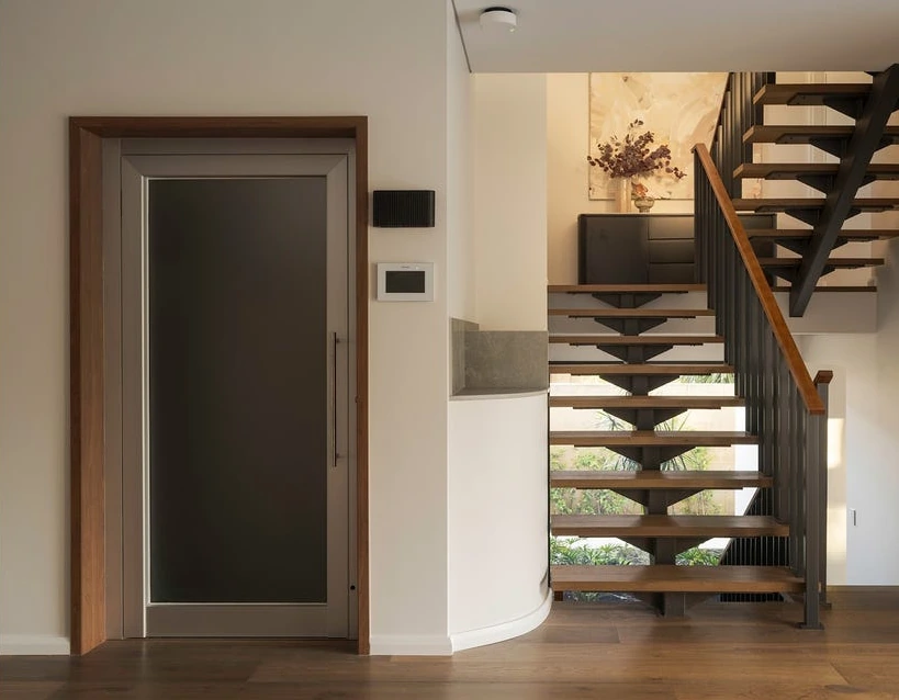A Series home lift beside a timber staircase in a City Beach home, Perth