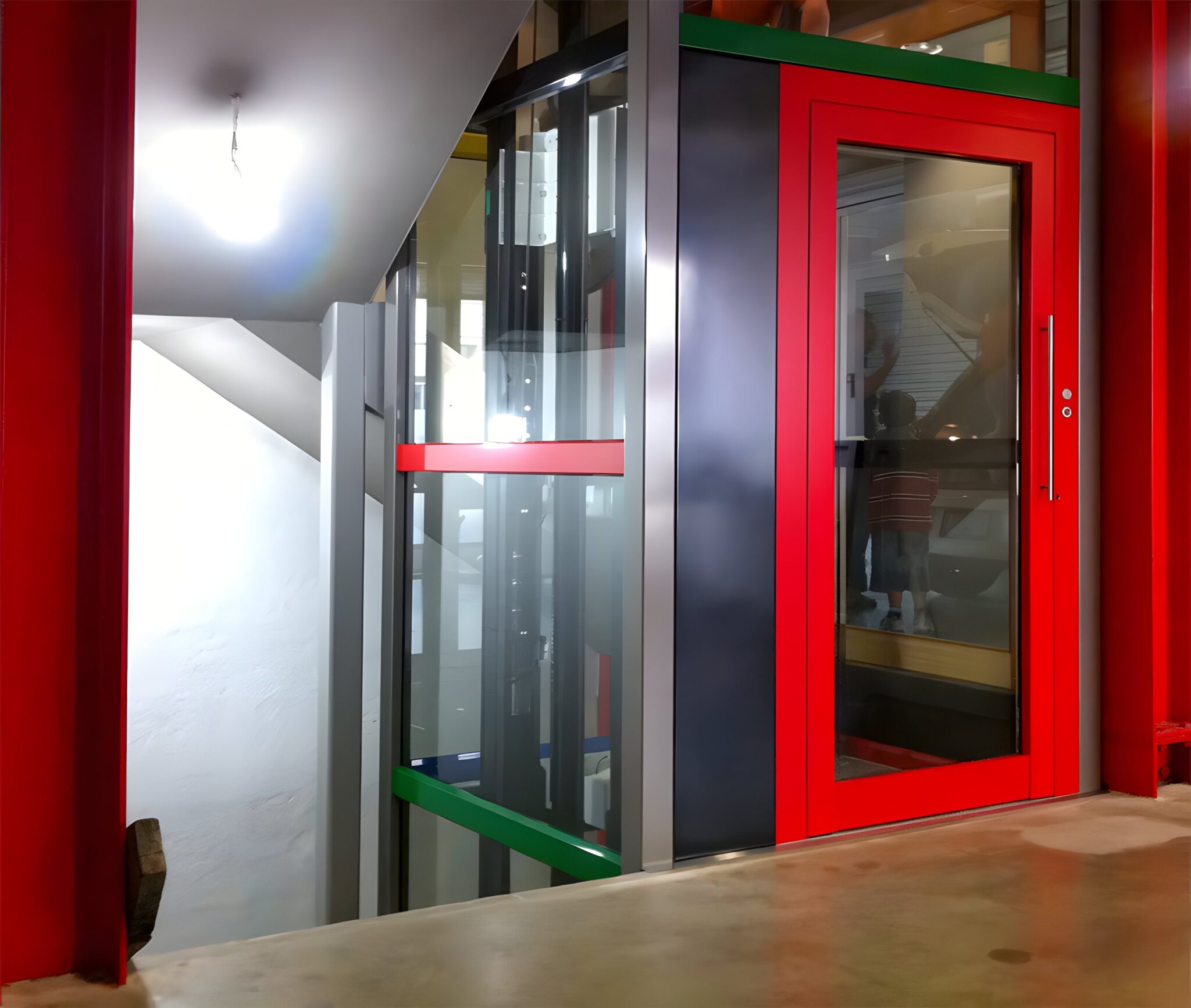 Bright red lift door and frame with a glass shaft beside the stairwell of a Carlton factory conversion