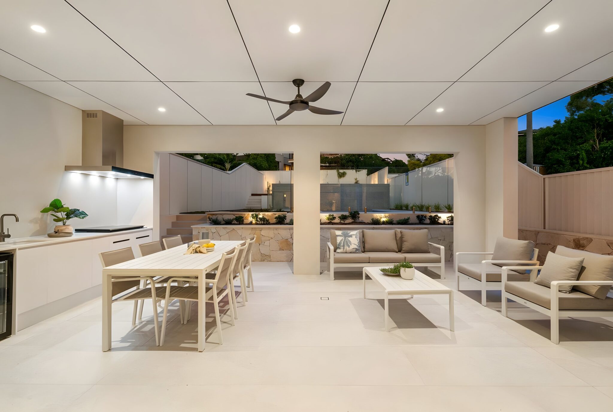 Covered alfresco area with a built-in kitchen, long dining table and lounge seating at the Connells Point duplex