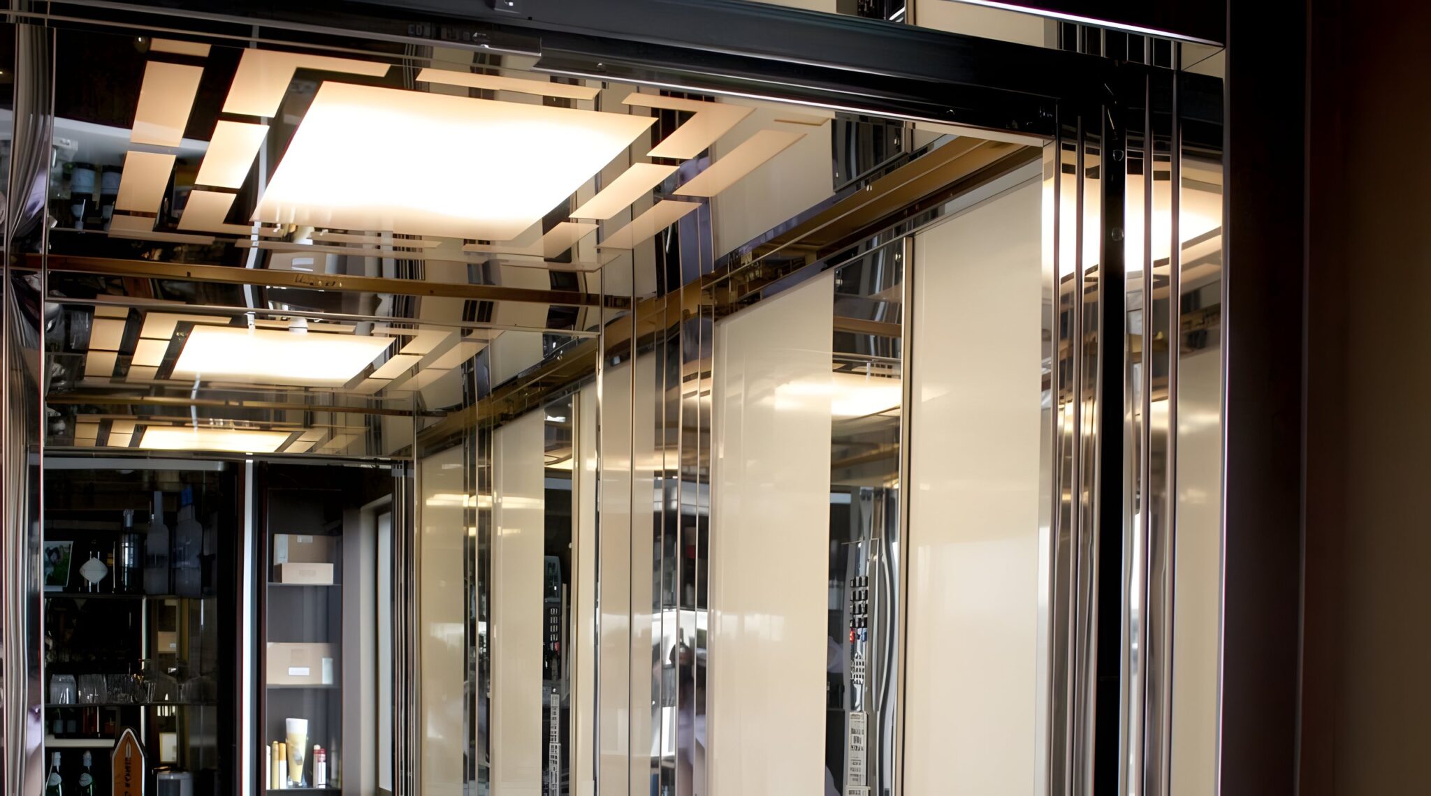 Mirrored lift cabin ceiling with a square light panel and polished stainless trim in the duplex