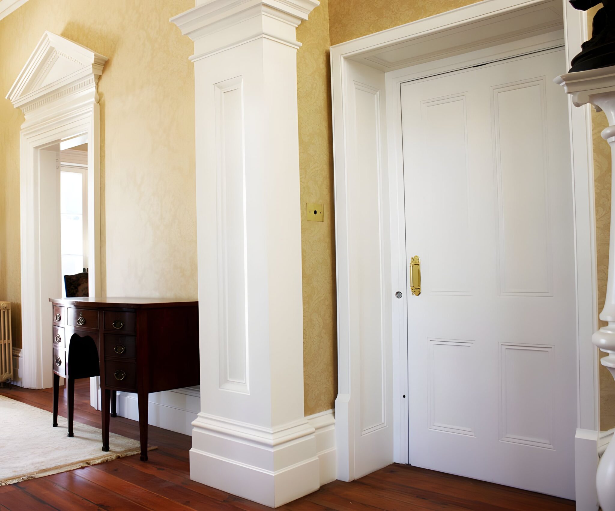 White panelled door beside a column and a dark timber console in the hallway of a heritage 1862 home