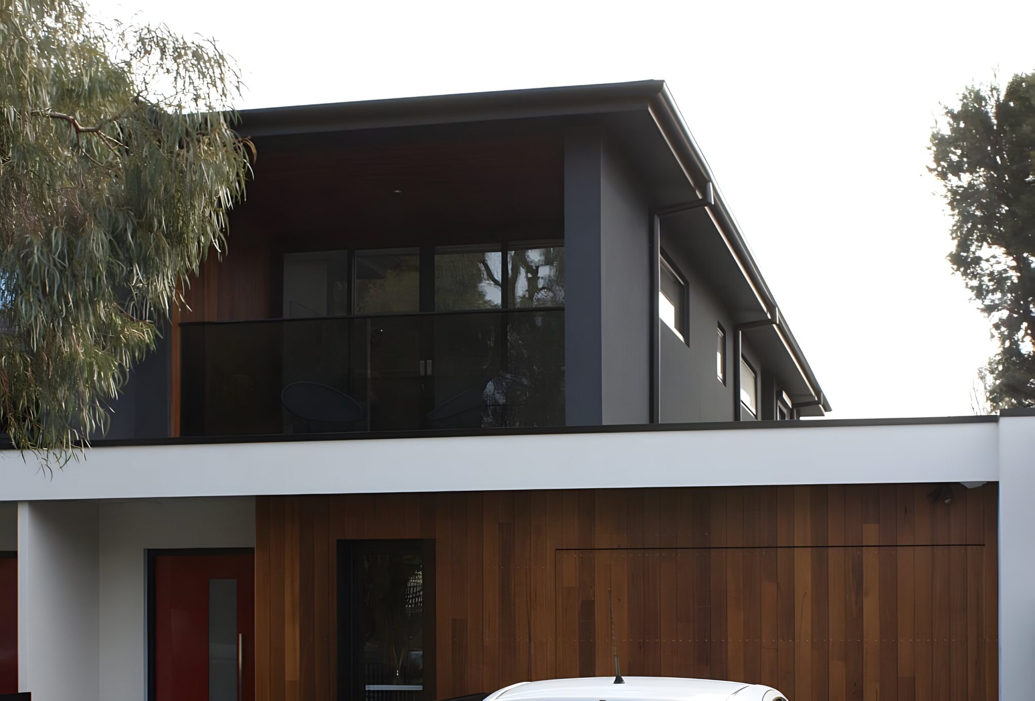 Two storey duplex with dark cladding and a timber garage door in Hampton