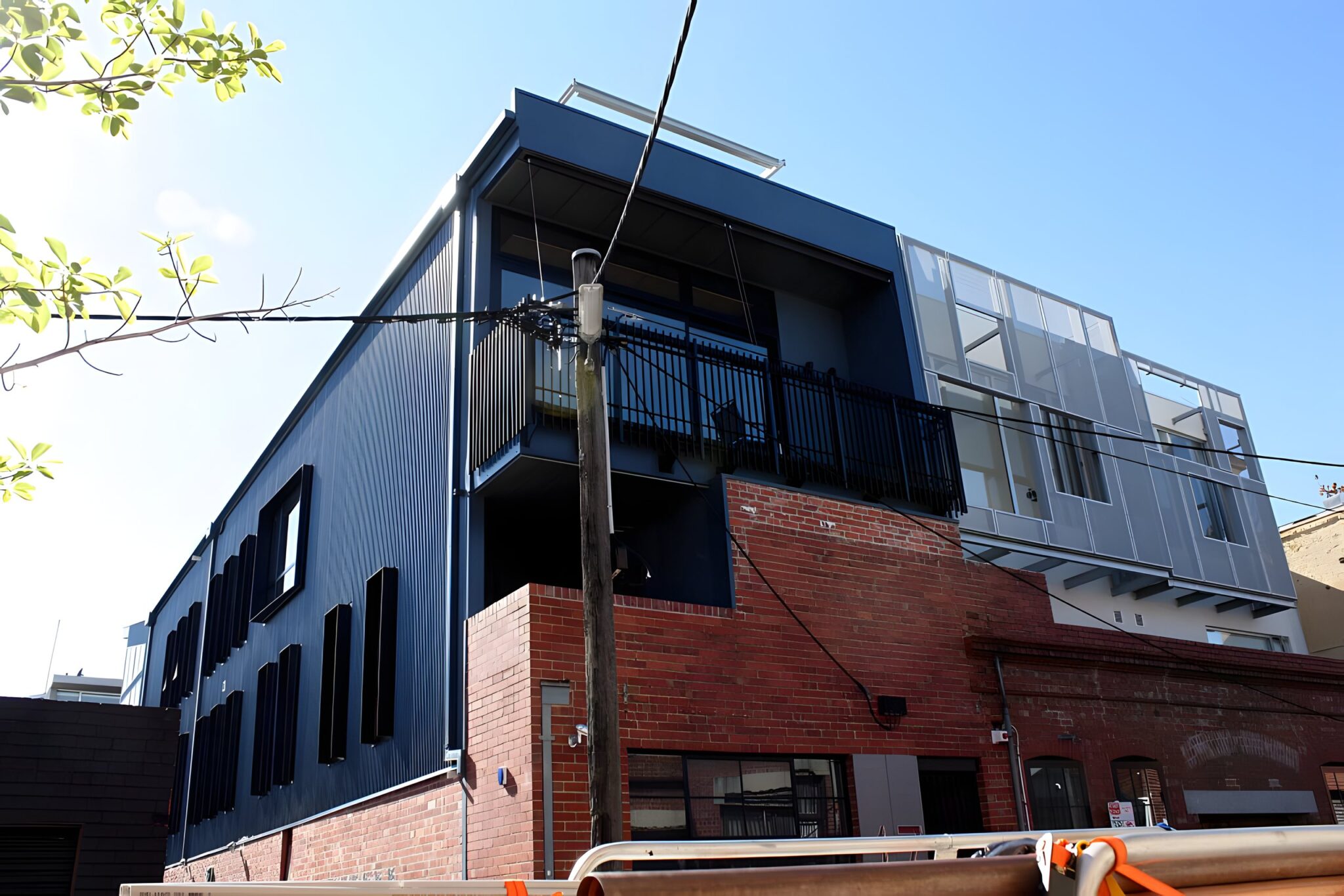Dark clad extension above an old brick building against a blue sky