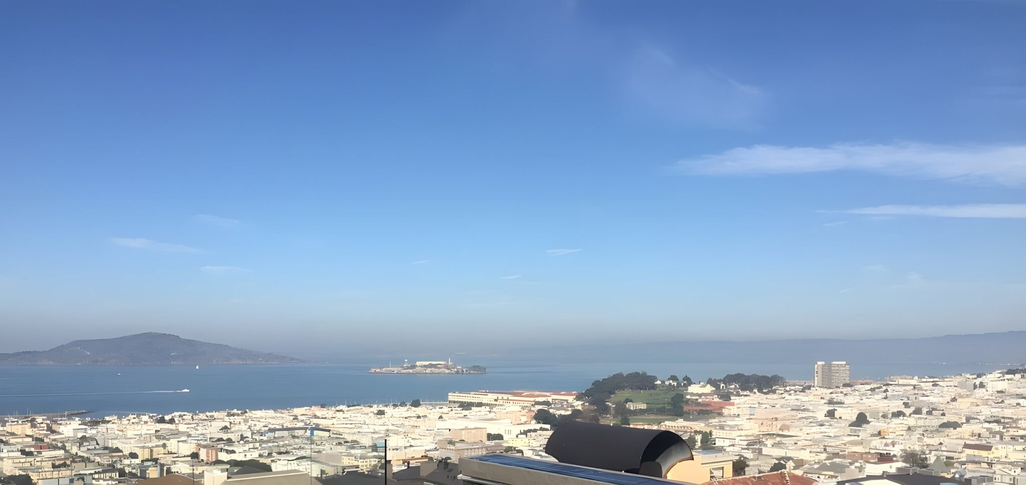 Panoramic view over San Francisco rooftops and the bay under a clear blue sky, seen from the home