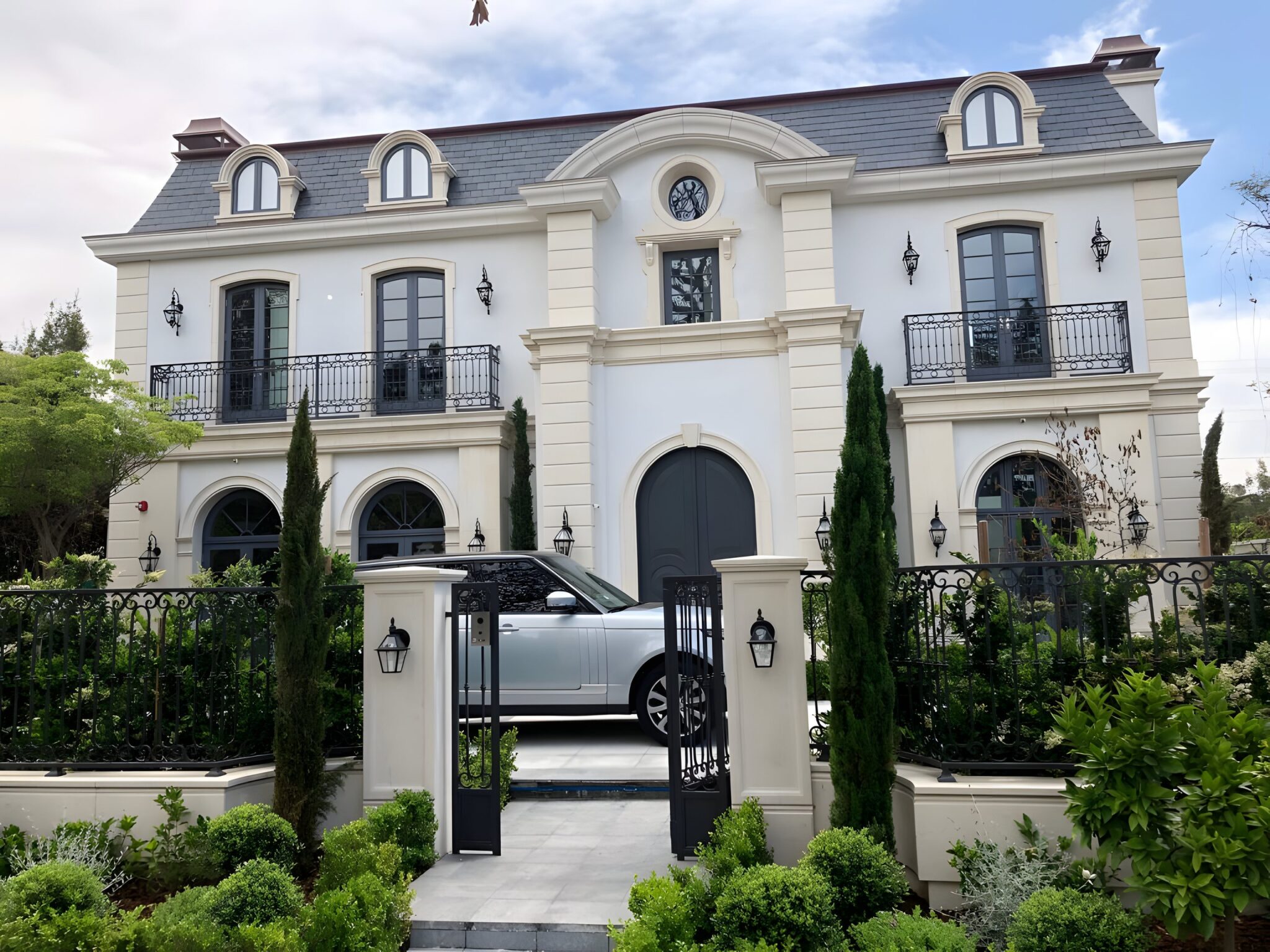 French-style two storey home with a slate roof, iron gates and clipped hedges in Beverley Hills