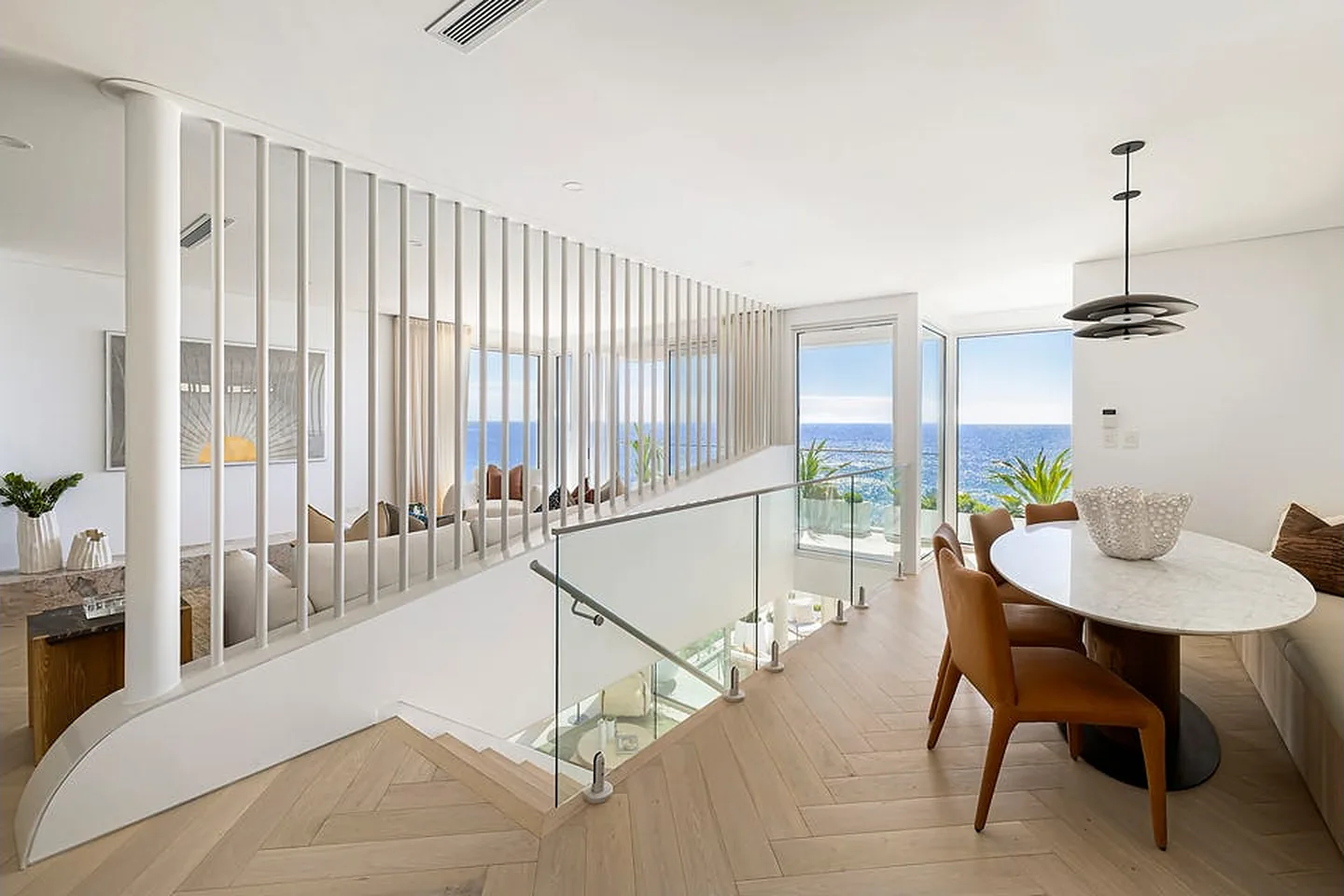 Open stair void and dining table with sea views in a Freshwater home Open stair void and dining table with sea views in a Freshwater home