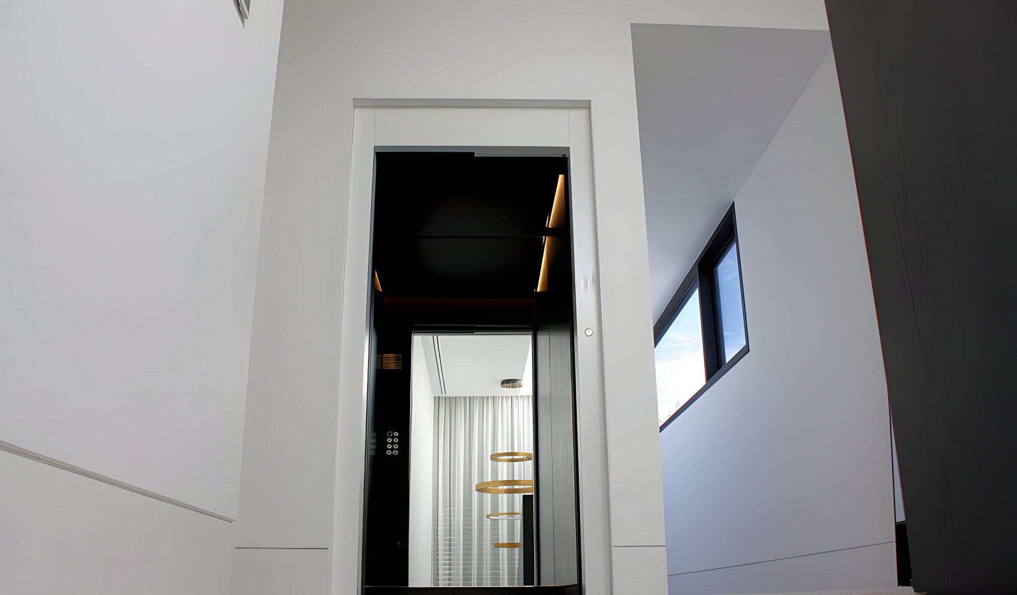 Black lift door with a glowing LED-lit cabin seen from a white landing in a Toorak home
