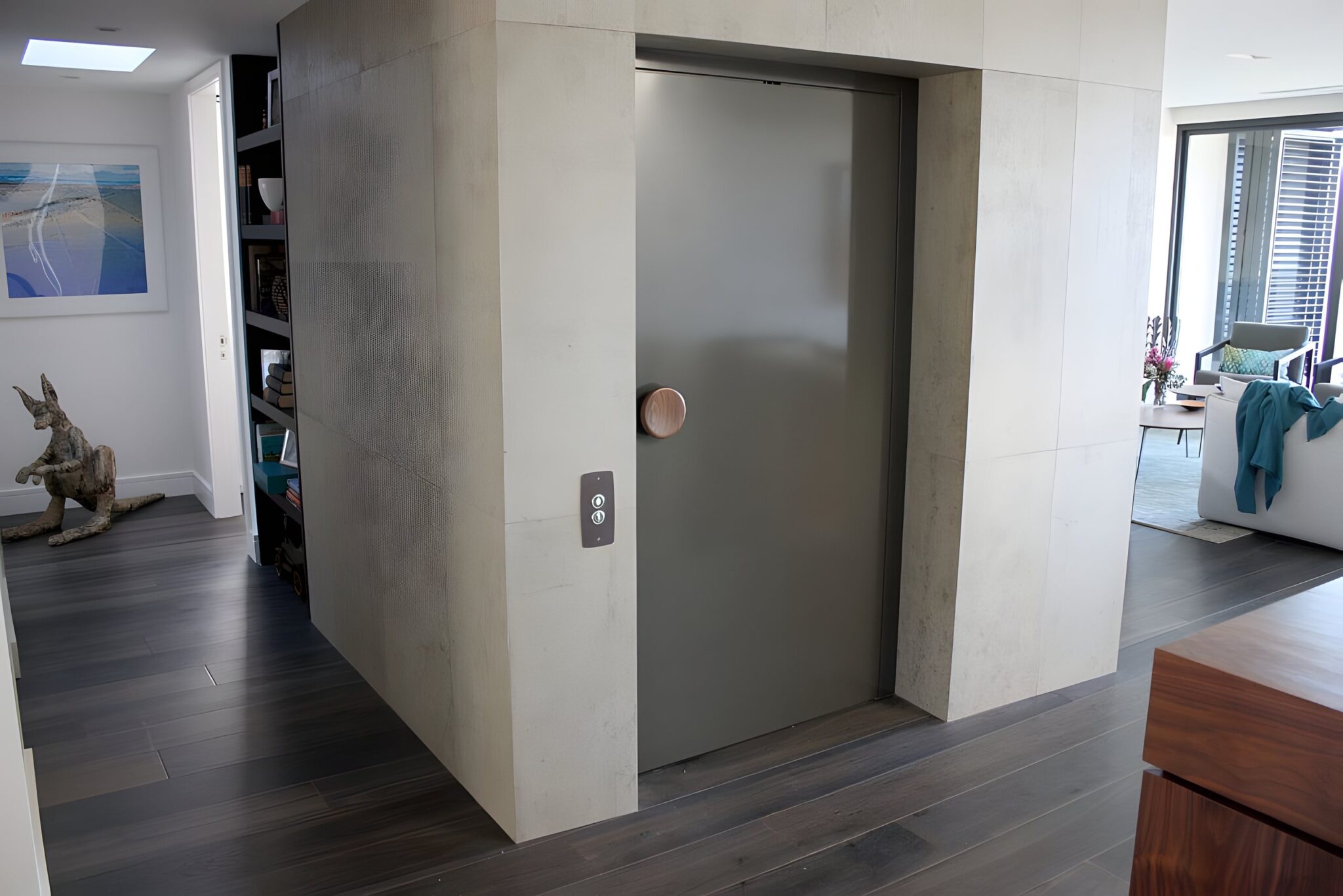 Lift door set in a pale stone-look enclosure with a round timber pull, in an Eastern Suburbs home