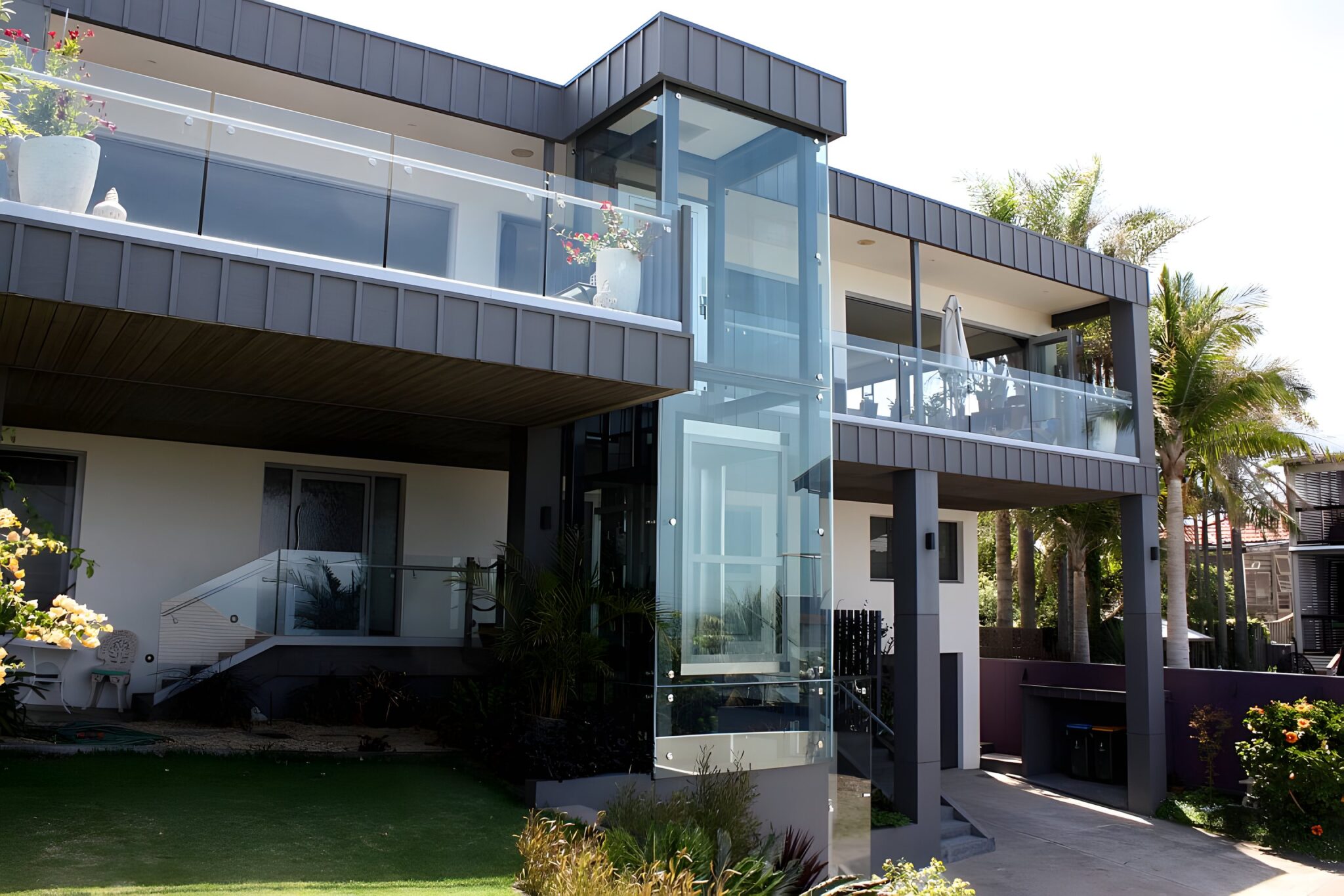 Three-storey house with a frameless glass lift shaft on the front between two balconies