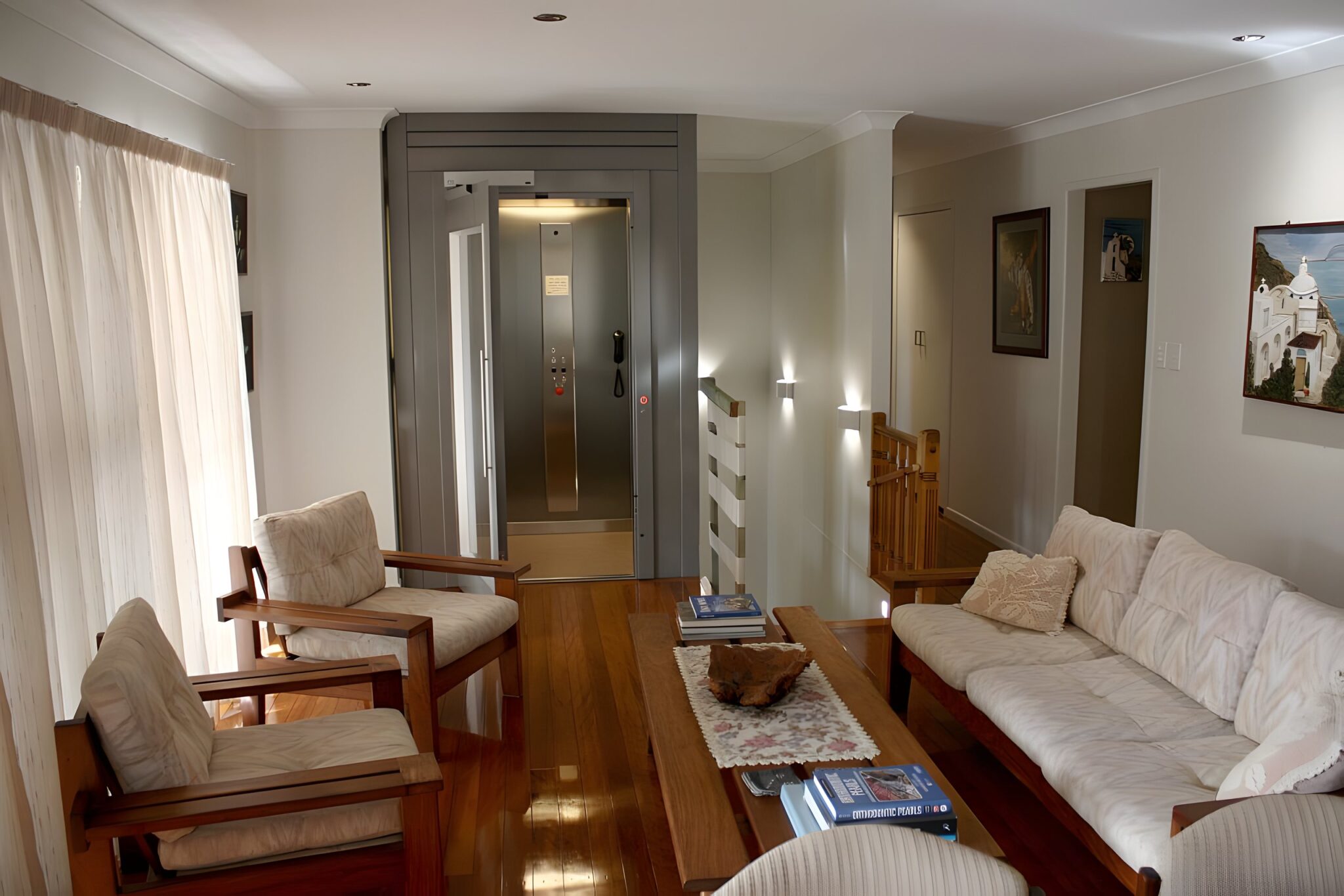 Living room with a timber floor and the retrofitted glass-shaft lift at the far end of the room