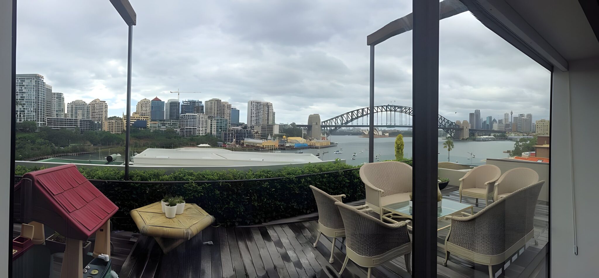 Harbour Bridge and the Sydney city skyline seen from a balcony with cane chairs at McMahons Point