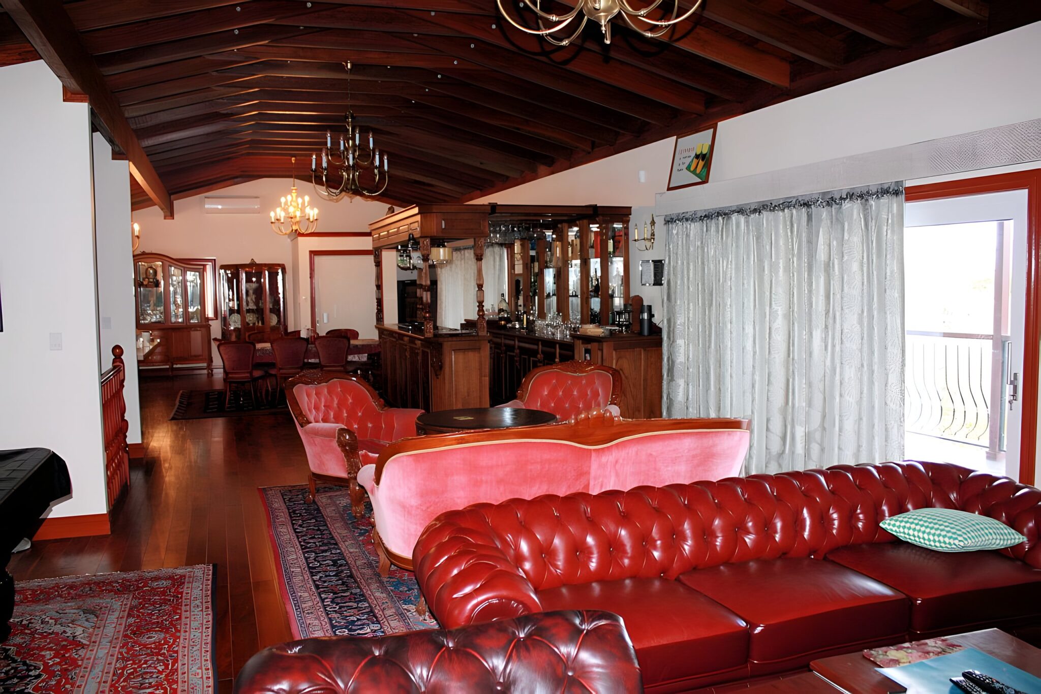 Living room with red leather Chesterfield sofas, a timber ceiling and chandeliers in a Brisbane home