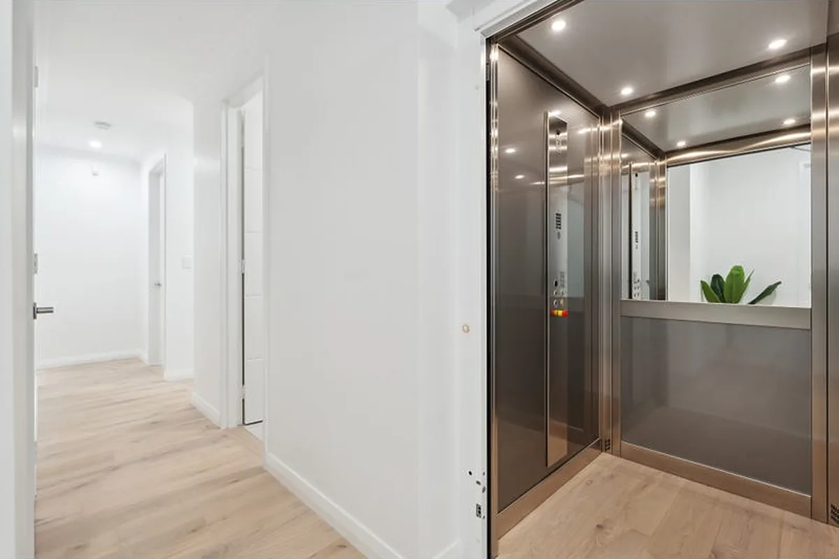 Open home lift cabin with brushed metal walls and mirror in Marmion