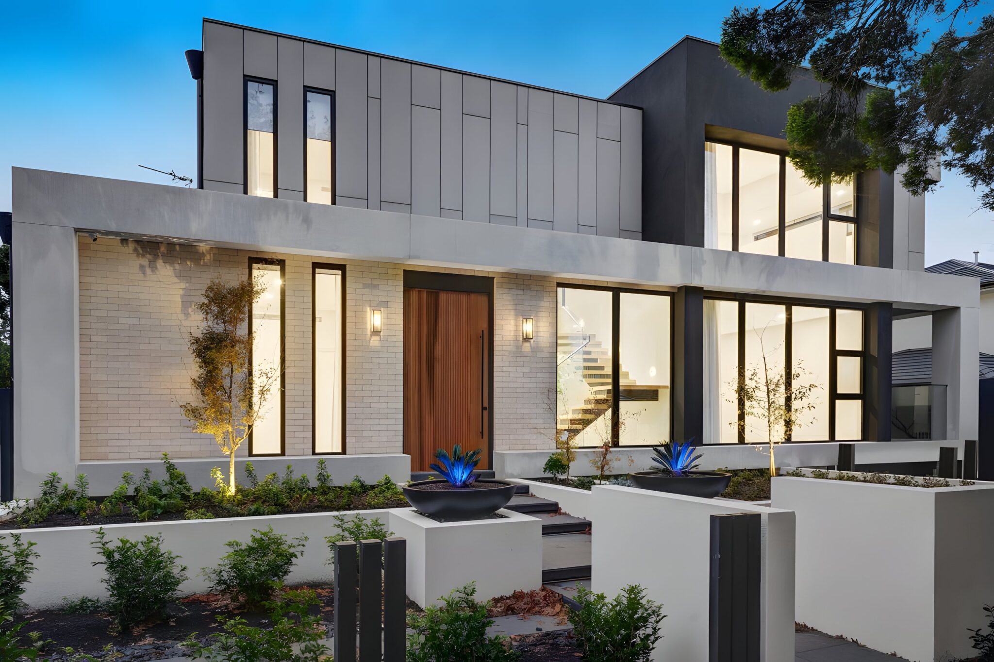Modern Mont Albert home with light brick, dark cladding and a timber front door at dusk