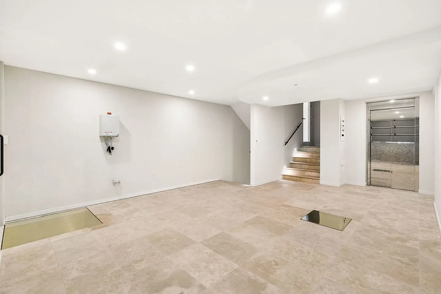 Lower level of a North Bondi home with polished lift doors beside the stair