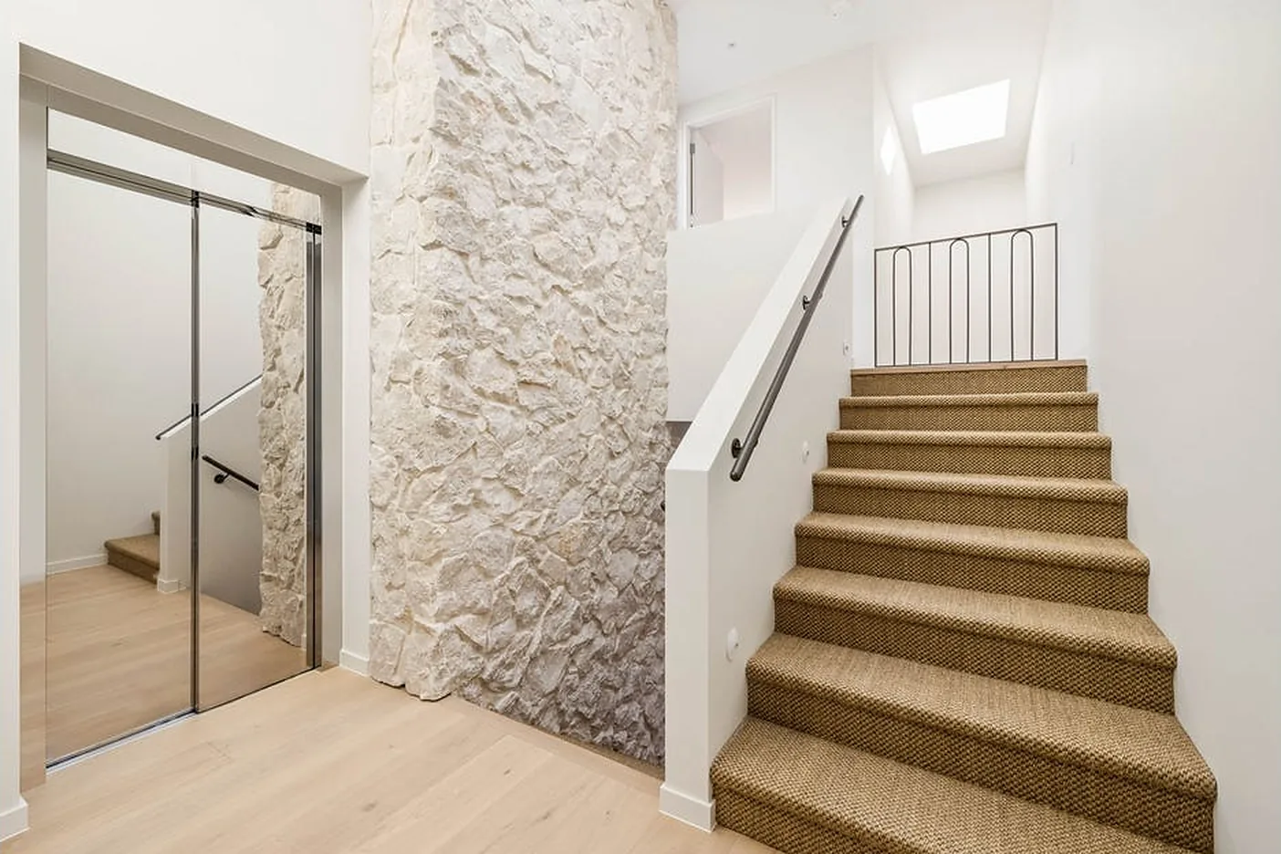 Mirror-bright sliding lift door beside a sandstone wall in North Bondi