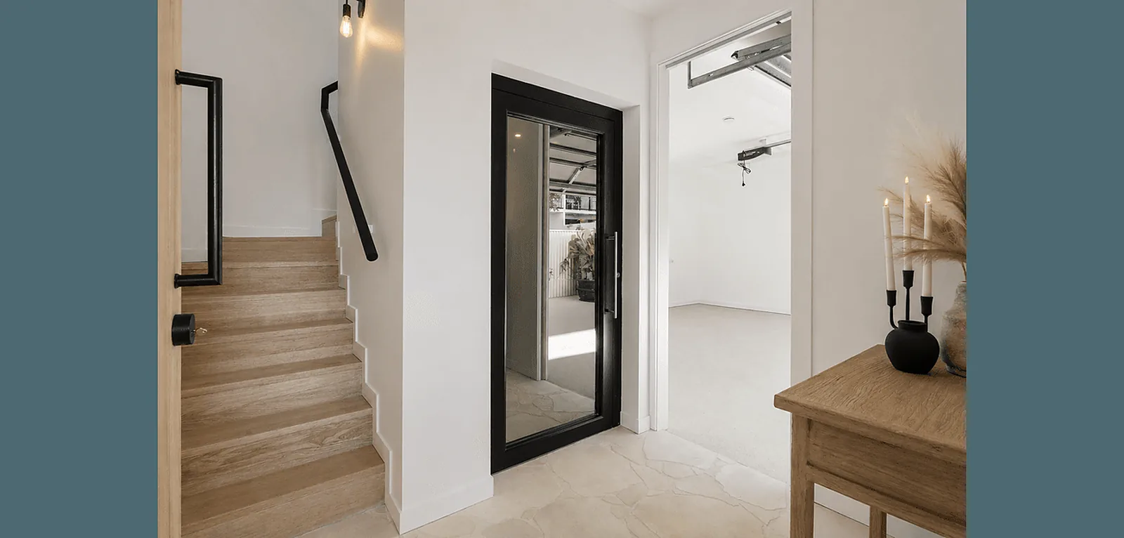 Black framed glass lift door beside the staircase in a Palm Beach townhouse