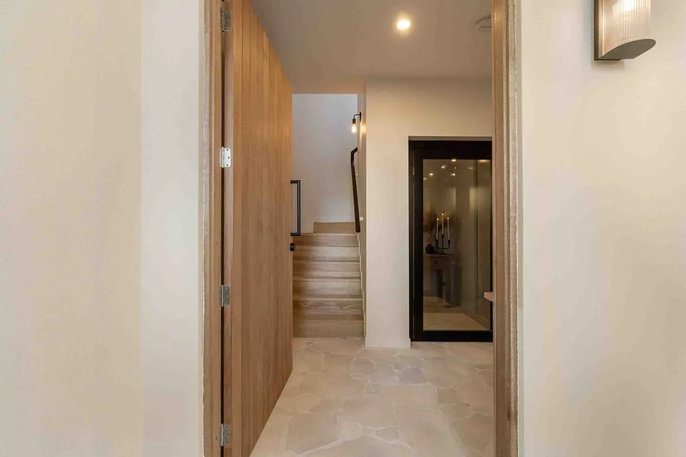 Hallway with timber door and black framed lift door beyond in Palm Beach