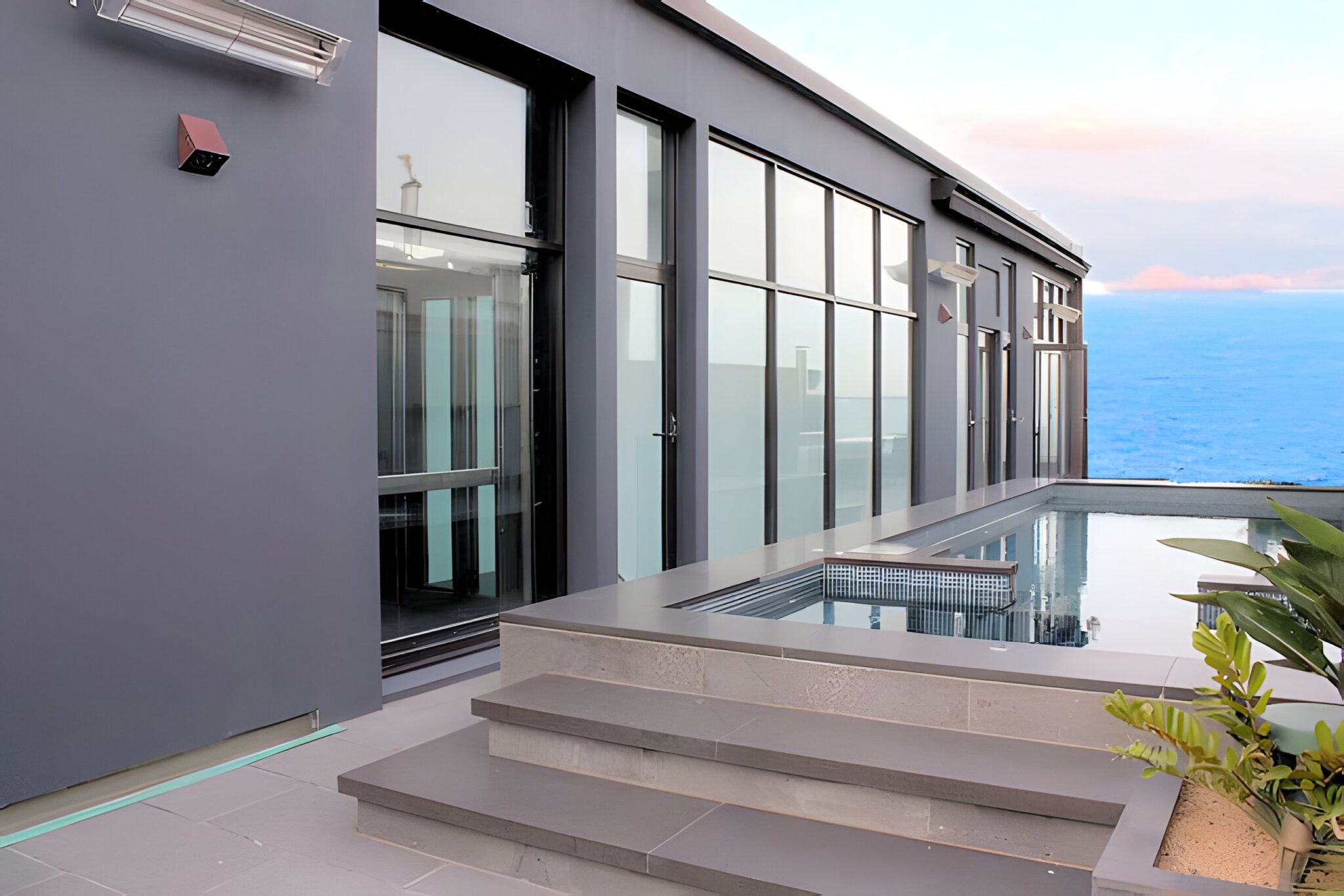 Rooftop terrace with a pool and sea view outside the glass doors of a lift at a Port Melbourne home