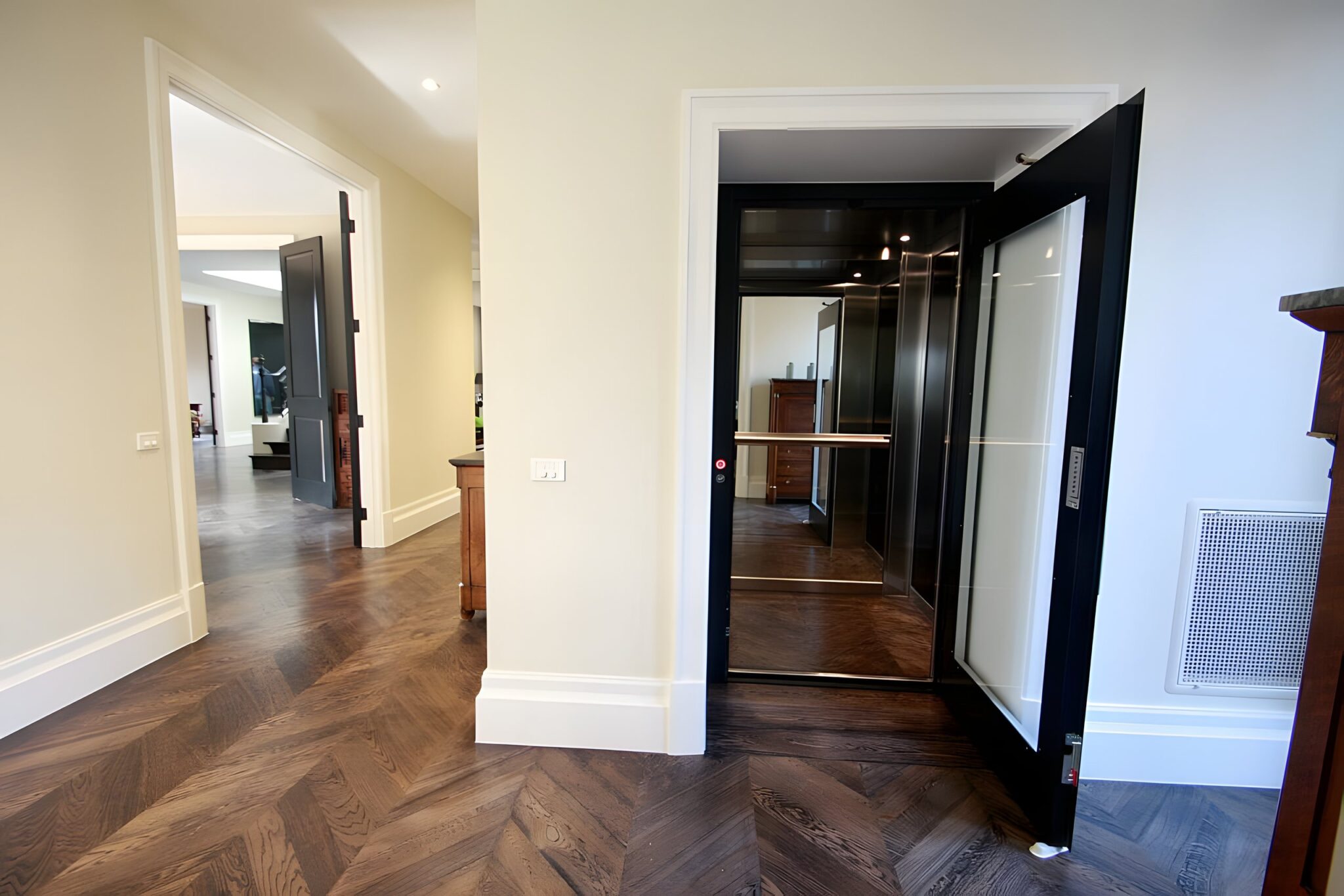 Open black-framed lift door with a glass panel beside a herringbone timber floor in a classic Melbourne home