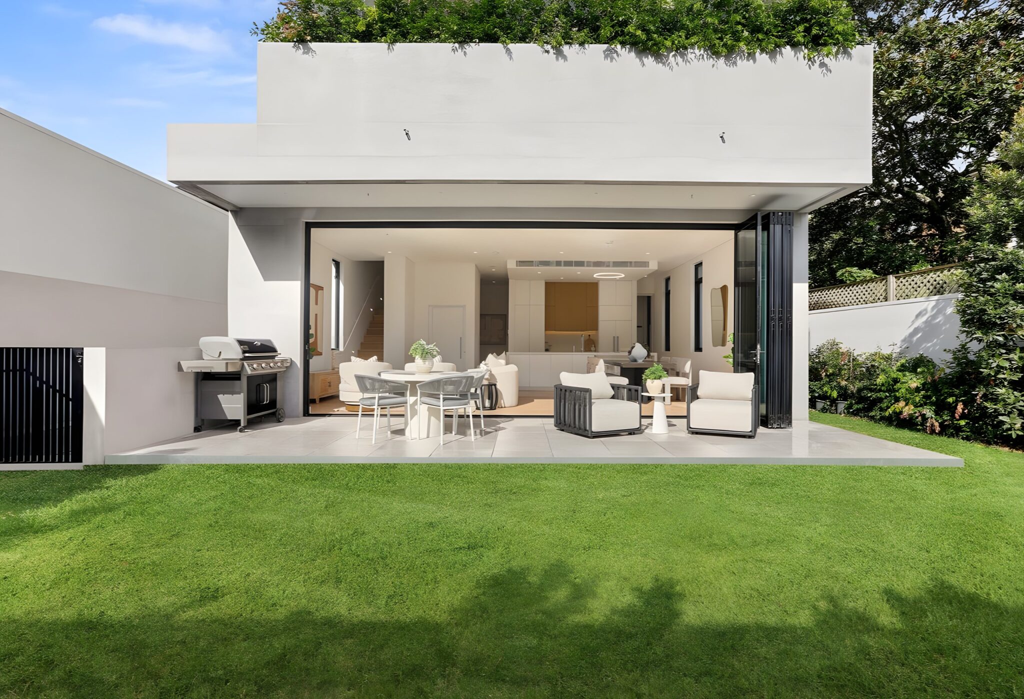 Rose Bay townhouse seen from the lawn, with the open-plan living area and outdoor entertaining terrace under a green-topped upper level