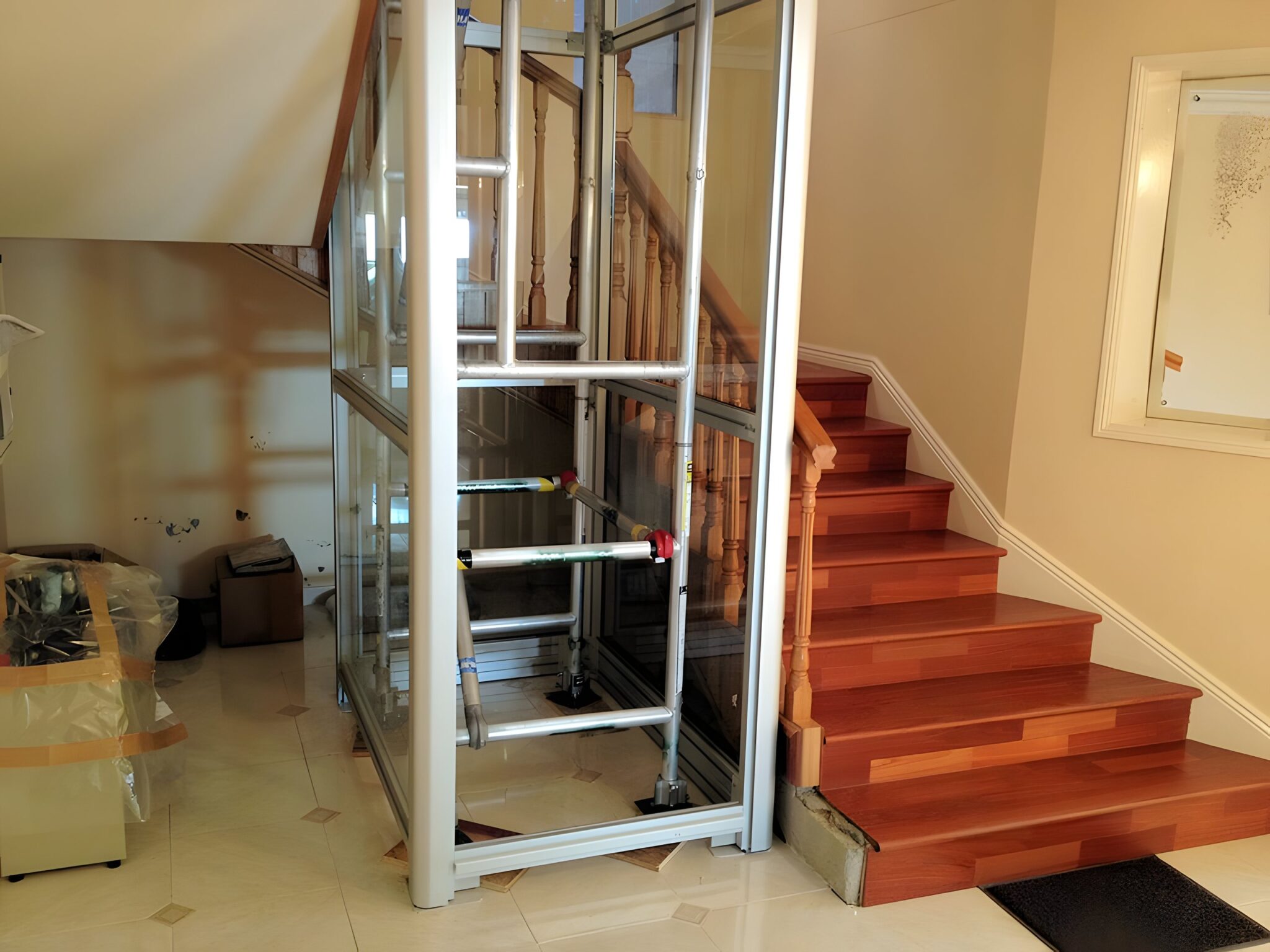 Glass lift shaft with an exposed aluminium frame beside a timber staircase in an existing home
