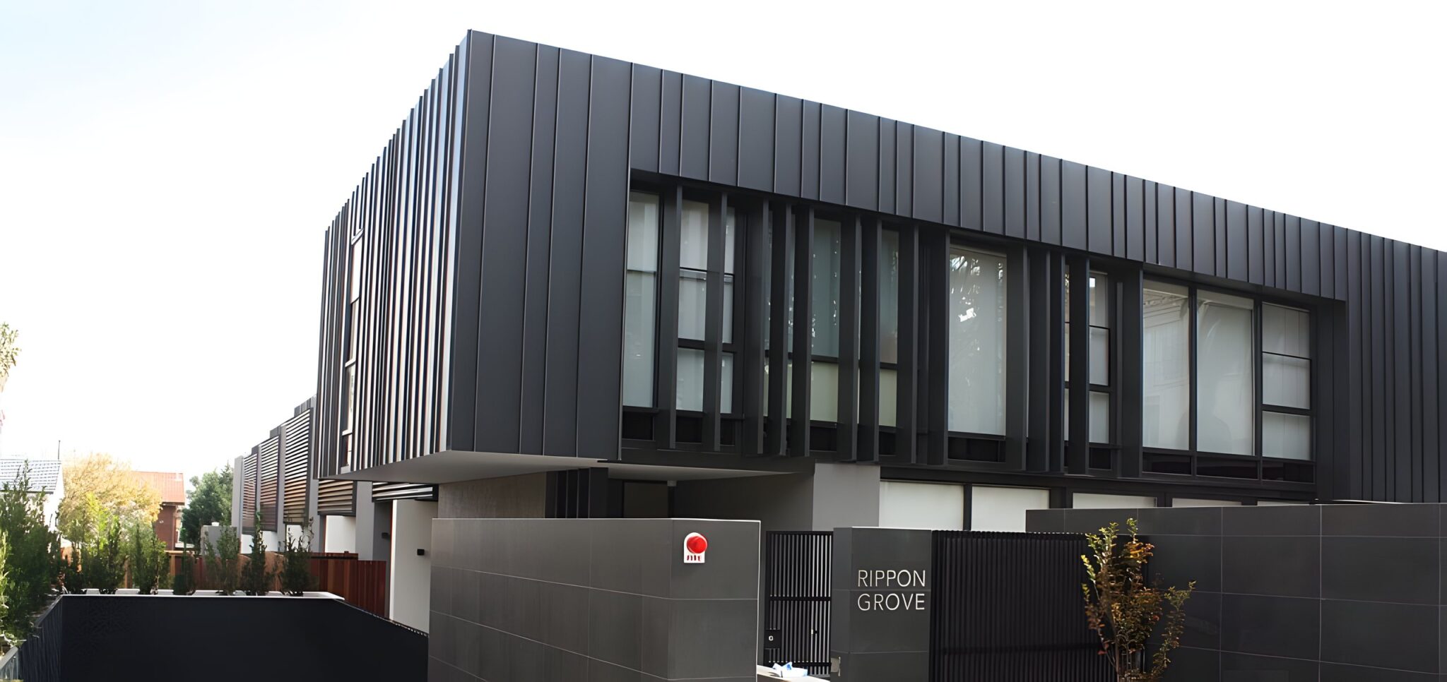 Dark metal-clad townhouse development with a gated entry in Brighton, Melbourne, home to seven lifts