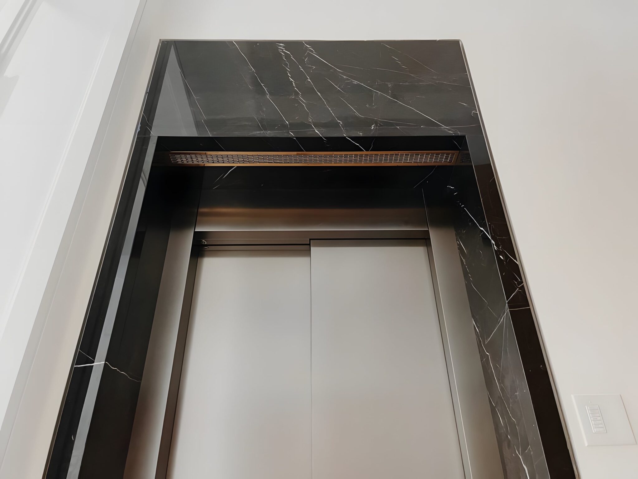 Black marble surround framing a stainless steel lift door in a Newport Coast home