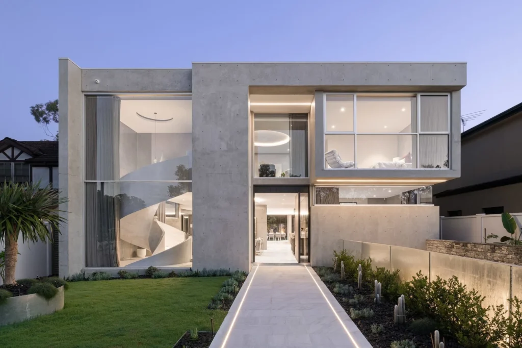 Concrete-clad contemporary new home lit at dusk in Strathfield