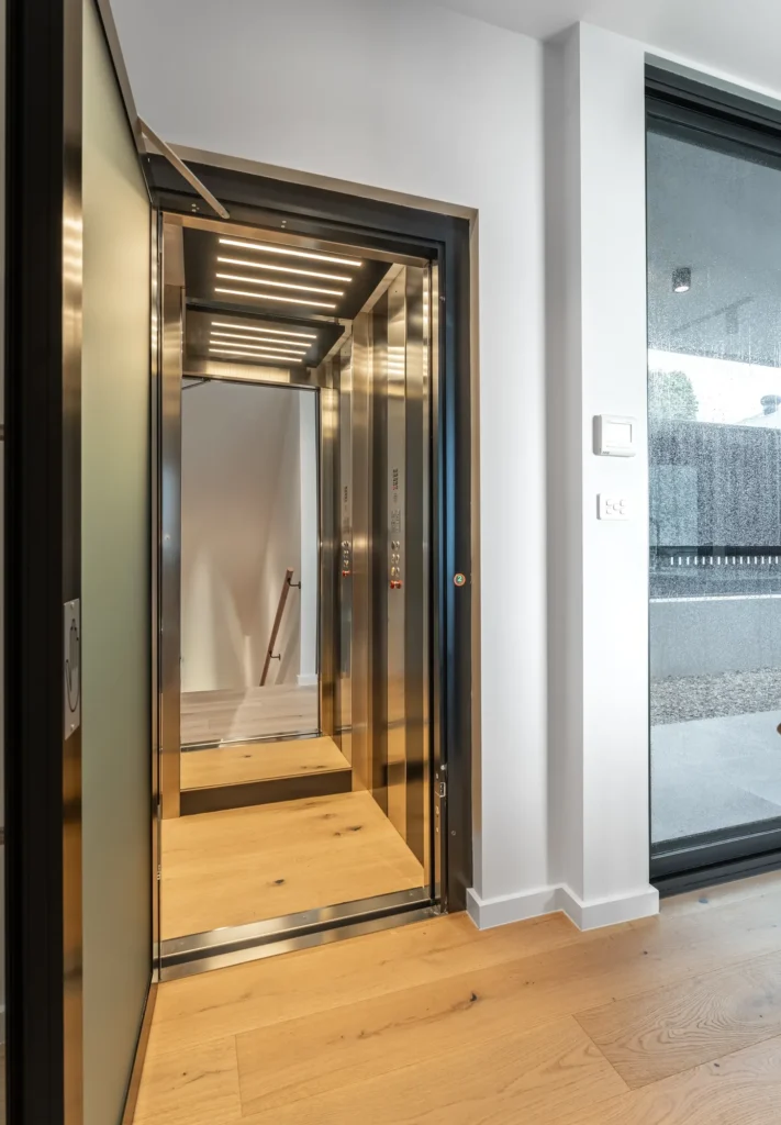 Open A Series home lift cabin with mirrored back wall, stainless trim and LED lighting