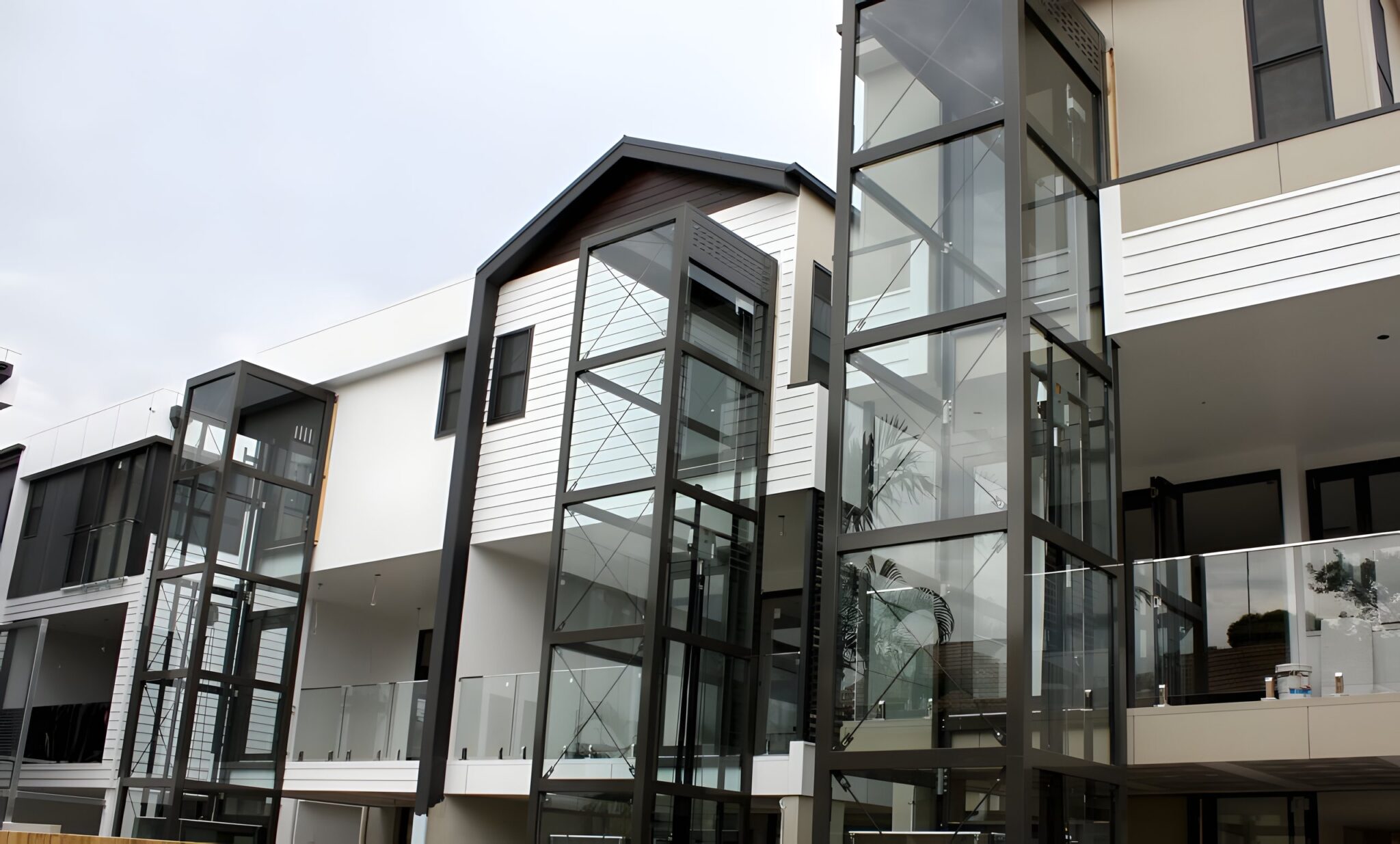 Row of New Farm townhouses with glass lift towers on the rear