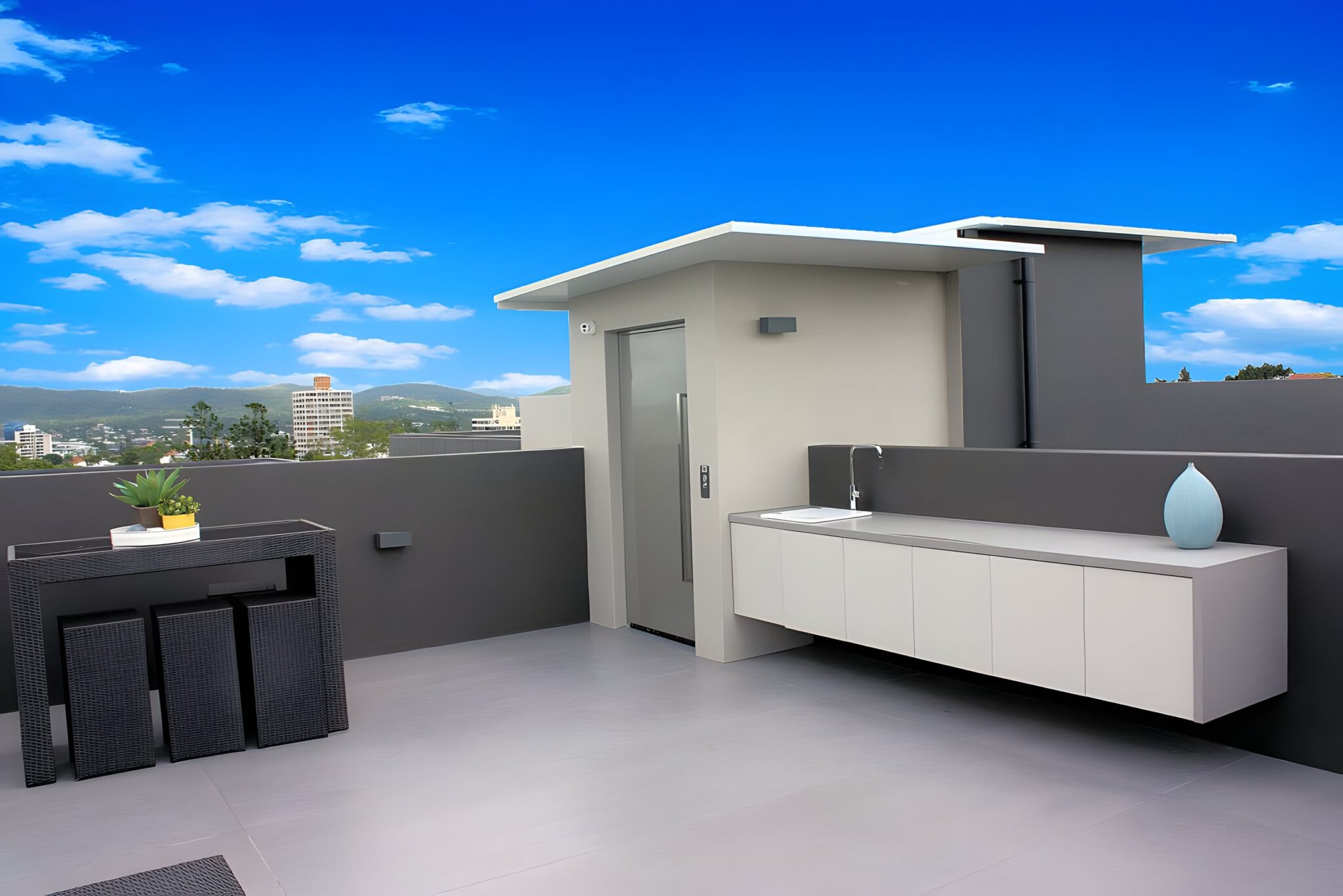 Rooftop terrace in Highgate Hill with the lift enclosure beside an outdoor bench and a view across Brisbane